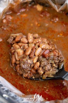 a spoon full of beans and meat in some sauce