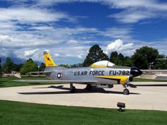 an air force jet sitting on top of a tarmac next to a grassy field