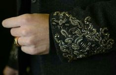 a close up of a person's hand wearing a gold and black cuff ring