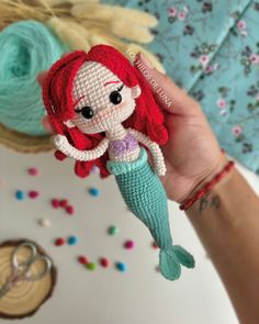 a crocheted little mermaid doll is held up to the camera