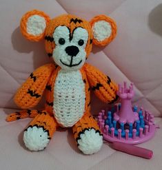 a crocheted stuffed animal sitting next to a comb and toothbrush on a bed