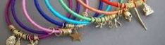 several different colored bracelets with charms hanging on a wall next to a key chain