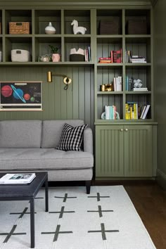 a living room filled with furniture and bookshelves next to a white rug on top of a hard wood floor