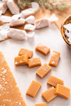 several pieces of cheese sitting on top of a cutting board next to a bowl and spoon