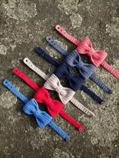 four small bow ties laid out on top of a stone surface, all in different colors and sizes