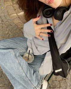 a woman sitting on the ground with headphones around her neck and wearing a tie