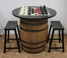 a chess set sitting on top of a barrel next to two stools and a table