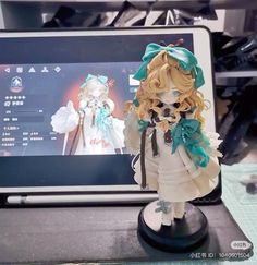 a doll is standing in front of a laptop computer with an anime character on the screen