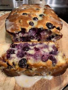 a loaf of blueberry bread sitting on top of a wooden cutting board