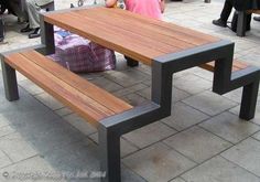 a person sitting at a wooden table on the sidewalk