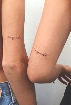 two women with matching tattoos on their arms and legs, both showing the words together