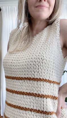 a woman with blonde hair wearing a white and brown striped knitted sweater looking at the camera