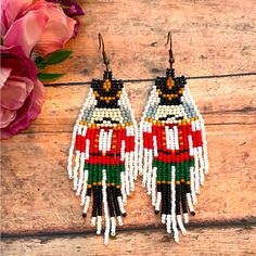 the beaded nutcracker earrings are on display next to pink flowers and petals