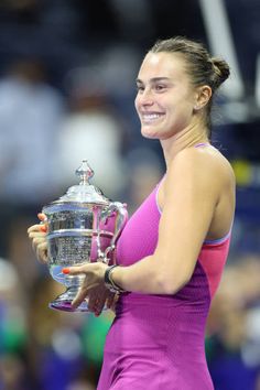 a female tennis player holding a trophy and smiling