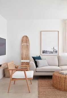 a living room with white walls and wooden furniture in the center, along with a surfboard mounted on the wall