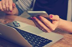 a woman using her cell phone while sitting in front of a laptop with the text how to trace mobile number location online free?