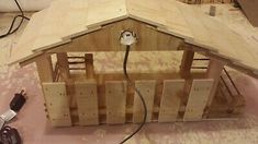 a house made out of wooden pallets on the floor with power cord plugged in