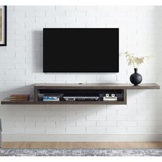 a flat screen tv mounted to the side of a wall next to a vase with flowers