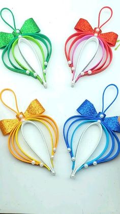 four different colored hair clips in the shape of hearts with bows on each one side