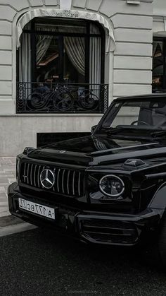 a mercedes g - class parked in front of a building