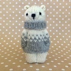 a knitted polar bear with a scarf around it's neck on a polka dot background