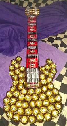 a guitar made out of chocolates sitting on top of a checkered bed sheet