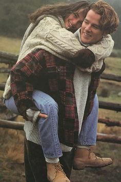 a man carrying a woman on his back in front of a fence and grass field