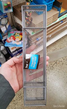 a person holding up a metal container with toothpaste on it in a store