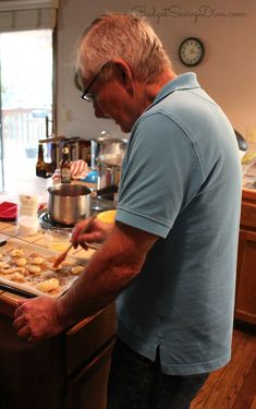 an older man preparing food in the kitchen with his hands on the counter and looking at it