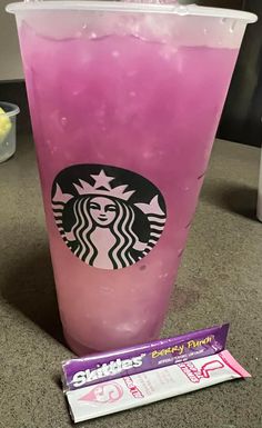 a pink drink sitting on top of a counter next to a wrapper