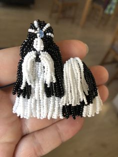 a hand holding a beaded brooch with a black and white dog on it