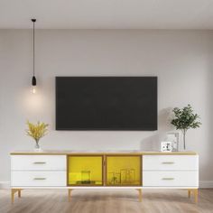 a television is mounted on the wall above a white cabinet with yellow doors and drawers