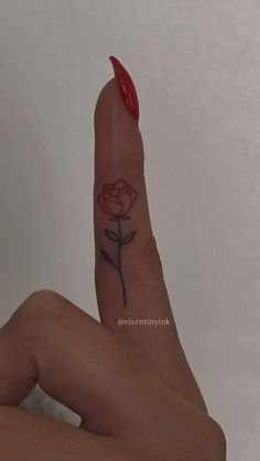 a woman's finger with a rose tattoo on it