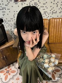 a young woman sitting on the floor next to a plate of cookies and muffins