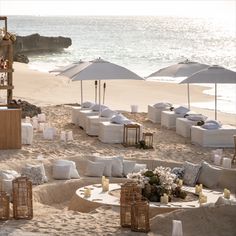 an outdoor seating area on the beach with chairs and umbrellas set up in the sand