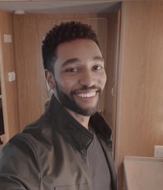 a man smiling and standing in front of a mirror with his hands on his hips