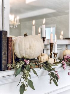 a white pumpkin sitting on top of a mantle next to some books and other decorations