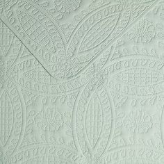 a close up view of an intricate pattern on a white wallpapered surface with light green paint