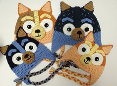 four crocheted animal hats are shown on a white surface, one is blue and the other is orange