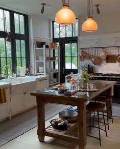 a kitchen filled with lots of counter top space and hanging lights above the stovetop