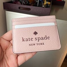 a person holding up a pink card case