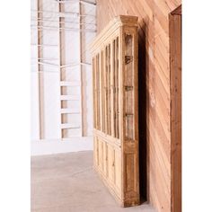 a wooden cabinet sitting in the corner of a room next to a wall with shelves on it