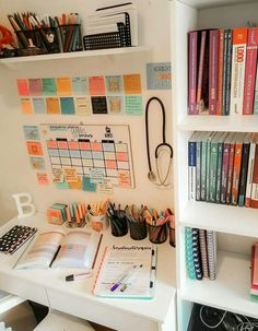 a white desk topped with lots of books next to a book shelf filled with books