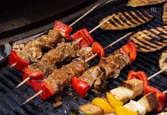 several skewers of meat and vegetables cooking on a grill