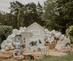 there is a barn with balloons and other decorations on the grass in front of it