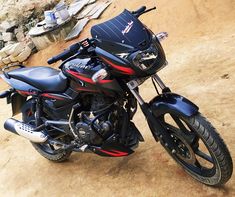 a black and red motorcycle parked on top of a dirt field