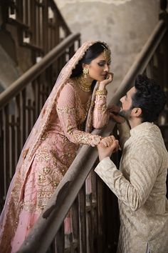 a man and woman standing next to each other in front of a stair case,