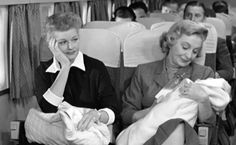 black and white photograph of two women sitting on an airplane with their baby in the lap