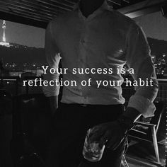 a man standing on top of a roof next to a tall building with the words your success is a reflection of your habit