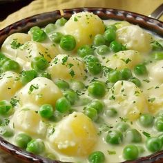 a bowl filled with peas and dumplings on top of a table